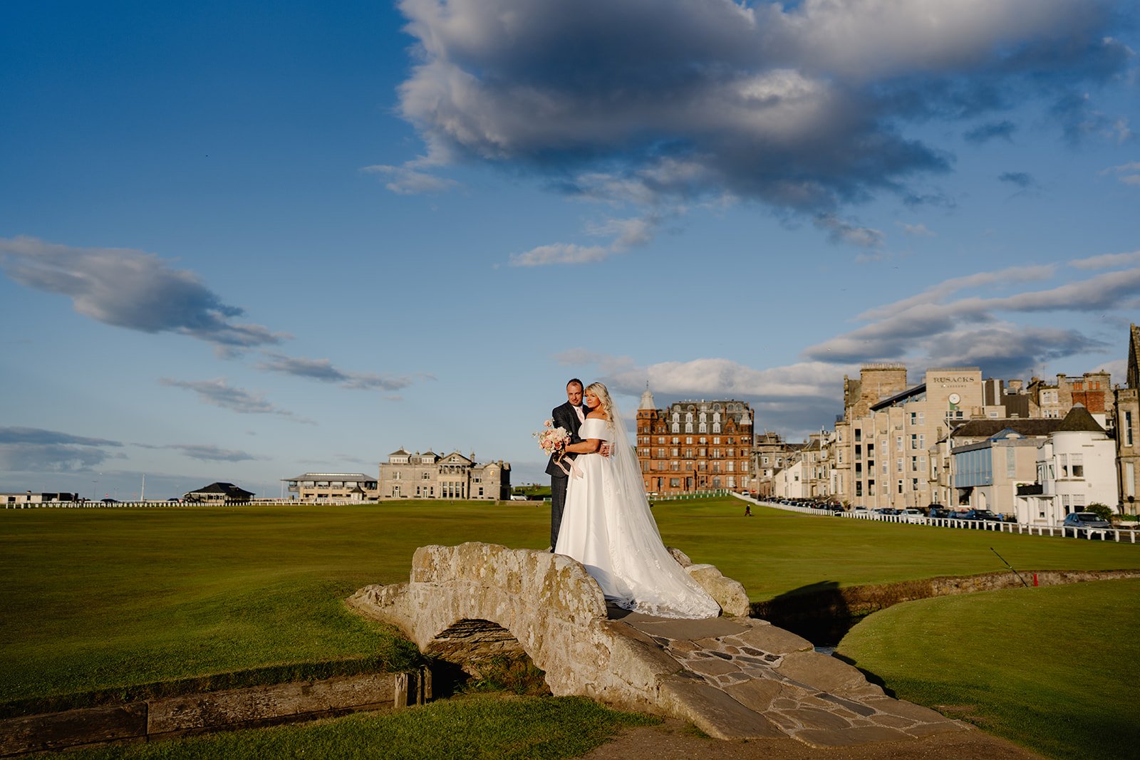 A bride and groom stand on the iconic Old course Bridge in St Andrews on their wedding day